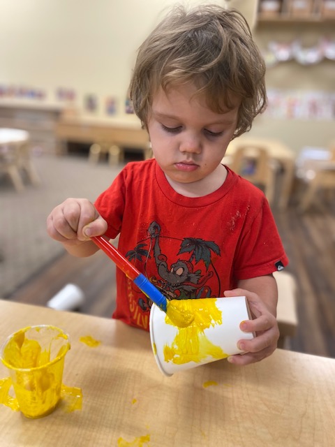 A child painting a paper cup.
